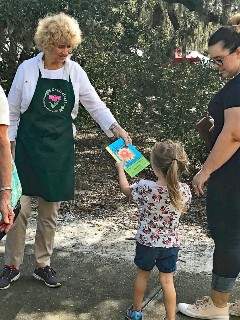 Jan Schubert handing book to a little girl