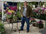 Man standing next to a table with yellow and pink orchids at gardenfest